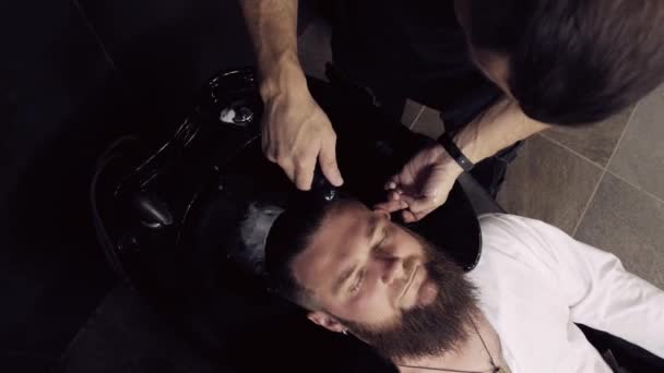 Vista superior de un barbero lavando la cabeza de un cliente masculino en una barbería. — Vídeos de Stock