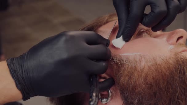 Siyah eldivenli berber tıraş köpüğüyle müşterinin sakalını tıraş eder.. — Stok video