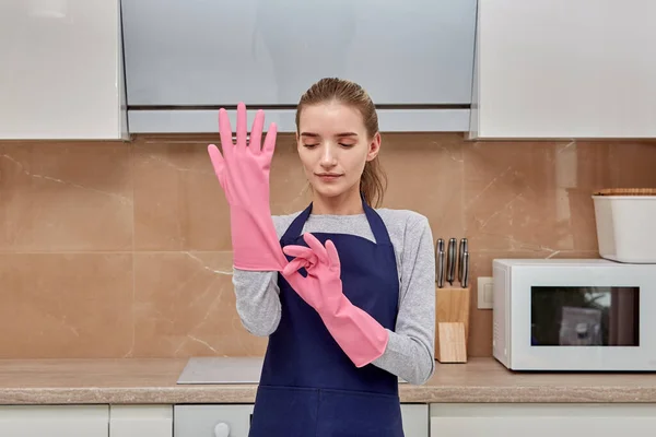 Jonge vrouw voor te bereiden op het reinigen, het zetten van handschoenen op haar handen voor het reinigen. — Stockfoto