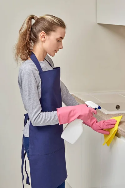 若い女性のプロの掃除機はスプレーでキッチンで掃除をします. — ストック写真