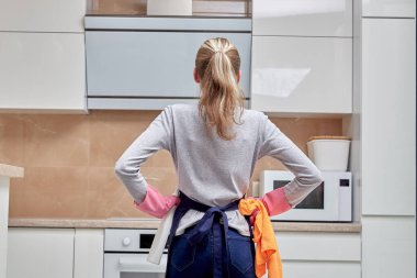 Bir kadın arkasını dönmüş mutfakta temizlik yapıyor..