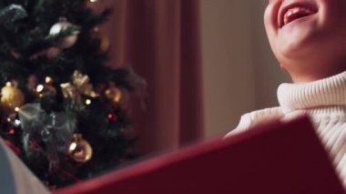 Neşeli bir çocuk güler ve büyük bir kitaptan Noel hikâyesi okur..
