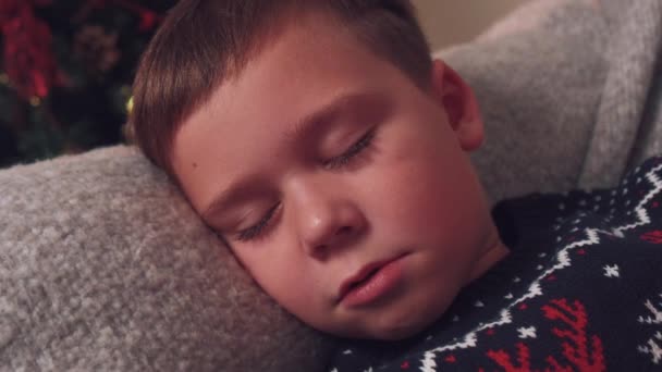 Aranyos, gyönyörű fiú elaludt a kanapén karácsony reggelére várva.. — Stock videók