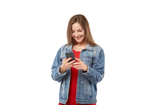 Gelukkig jong blond vrouw glimlacht en kijkt naar de mobiele telefoon scherm. — Stockfoto