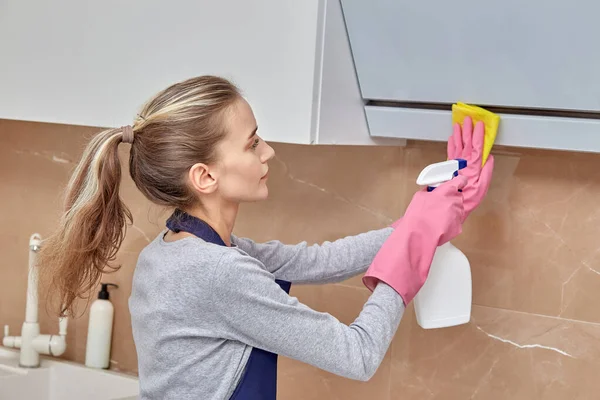 Limpiador de mujeres lava la campana en la cocina con productos químicos para el hogar en aerosol. — Foto de Stock