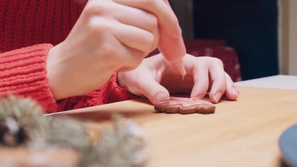 Close-up van de handen schilderen kerstboom-vormige koekjes met roze crème. — Stockvideo