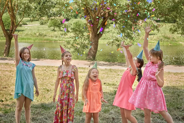 Девочки блюют конфетти на детской вечеринке в летнем парке. — стоковое фото