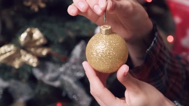 Bela bola de Natal cor de ouro brilhante nas mãos das mulheres com uma manicure curta. — Vídeo de Stock