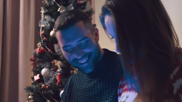 Een jonge mooie vrouw opent een kerstcadeau, het gloeit met een helder licht. — Stockvideo