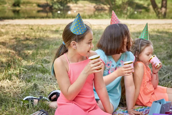 En tjej i partyhatt med läsk i en bägare firar sin födelsedag. — Stockfoto