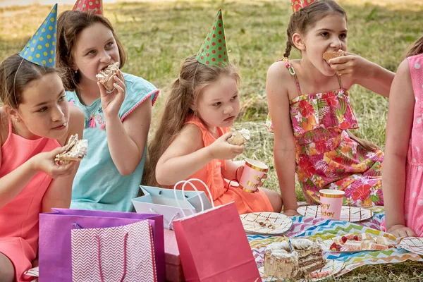 Дети едят торт на дне рождения друзей в шапочках для вечеринок. — стоковое фото