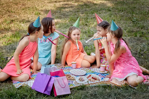 Glada tjejer på sommaren på gräset firar sin födelsedag i parken. — Stockfoto