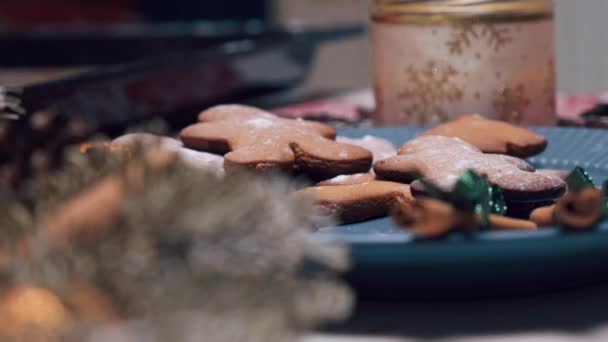 Uma mão feminina coloca biscoitos de gengibre recém-preparados em um prato turquesa — Vídeo de Stock
