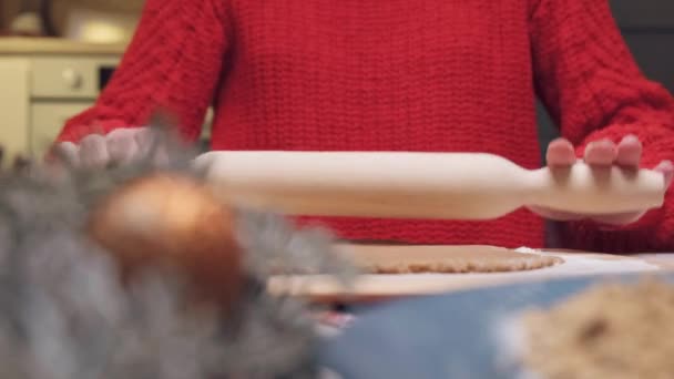 Una joven con una chaqueta roja prepara masa para las galletas de Navidad. — Vídeo de stock
