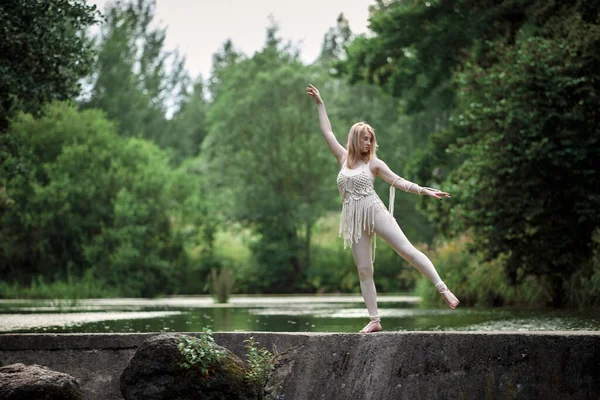 Belle fille blonde mince dansant sur le fond du lac et des arbres. — Photo