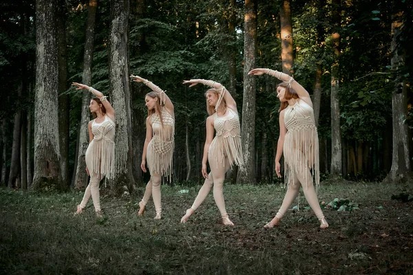 Quatre belles jeunes danseuses élancées dansent de façon synchrone dans la forêt. — Photo