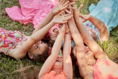 Kirli yüzlü komik kızlar ellerini kaldırarak çimlerin üzerinde yatıyorlar.