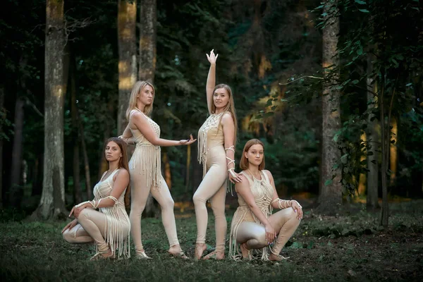 Quatre belles danseuses dans la forêt en costumes décorés de macramé. — Photo