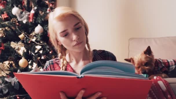 Χαριτωμένη όμορφη νεαρή γυναίκα κοιτάζοντας χριστουγεννιάτικο άλμπουμ φωτογραφιών. — Αρχείο Βίντεο