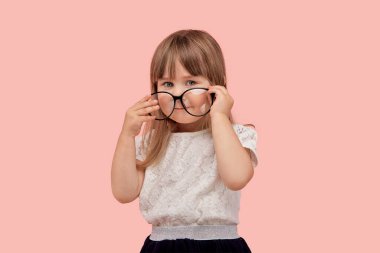 Kız görüş için büyük gözlük takıyor. Bir çocukta zayıf görme.