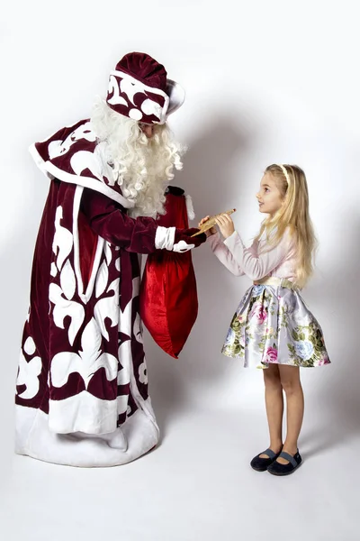 Menina em um lindo vestido recebe um presente de Papai Noel. — Fotografia de Stock