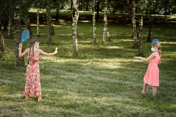 Twee meisjes spelen badminton met blauwe rackets op zomervakantie in het bos. — Stockfoto