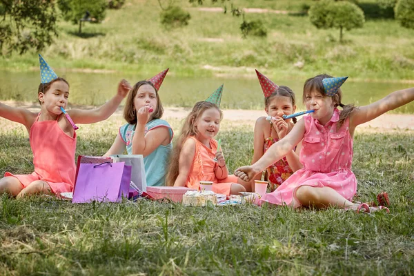 Fyra tjejer i semester hattar fira en vän födelsedag i naturen på sommaren. — Stockfoto