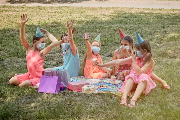 Celebración del cumpleaños de los niños en una máscara médica en la naturaleza. — Foto de Stock
