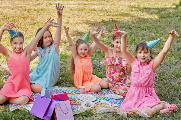 Девочки подняли руки, празднуя свой день рождения сидя на траве. — стоковое фото