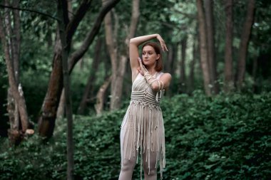 Genç ve güzel bir kadın makrome ile süslenmiş bir kostümle dans ediyor..