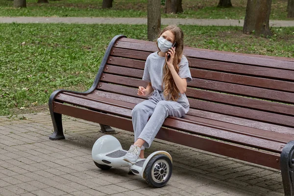 Menina bonita sentada em um banco no parque e falando ao telefone. — Fotografia de Stock