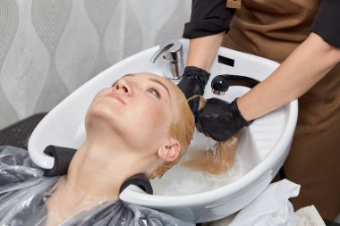 Berber şampuanı müşterinin suyuyla yıkar, ıslak sarı saçlarıyla..