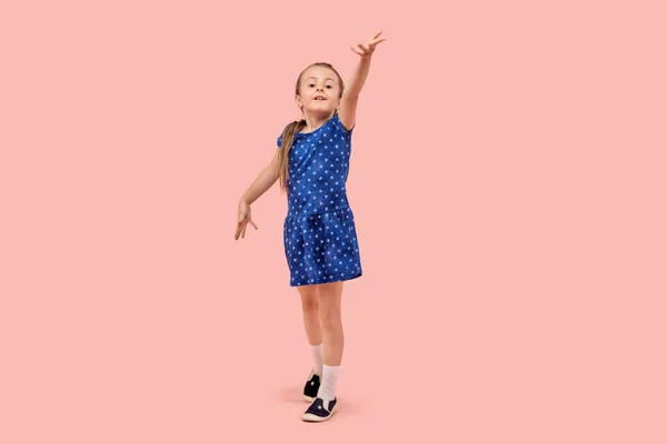 Портрет маленької дівчинки в красивій блакитній точковій сукні Полька. Рожевий фон . — стокове фото