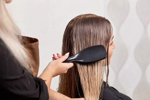 Fryzjer grzebień klienta jasne mokre włosy z grzebieniem po farbowaniu włosów. — Zdjęcie stockowe
