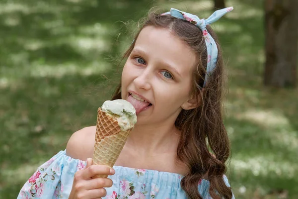 Vacker brunett flicka med söt glass i en våffla kon. Blå kläder. — Stockfoto