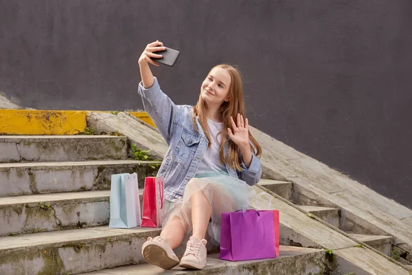 Uma jovem linda garota loira tira uma selfie e se comunica via link de vídeo. — Fotografia de Stock