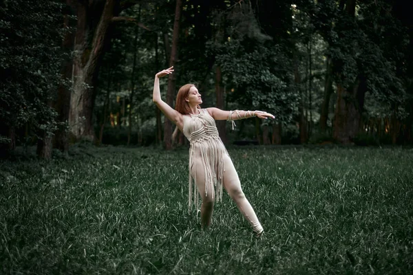 Kvinna i en beige klänning dansar på ett fält med blommor, makram i kläder. — Stockfoto