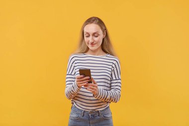 Elinde telefonla akıllı bir telefona bakan güzel bir genç kadın..