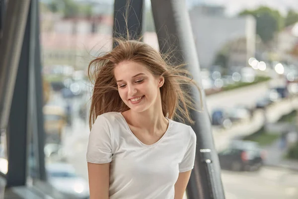 Una joven con el pelo largo y rubio sonríe. Cabello volando en el viento. — Foto de Stock