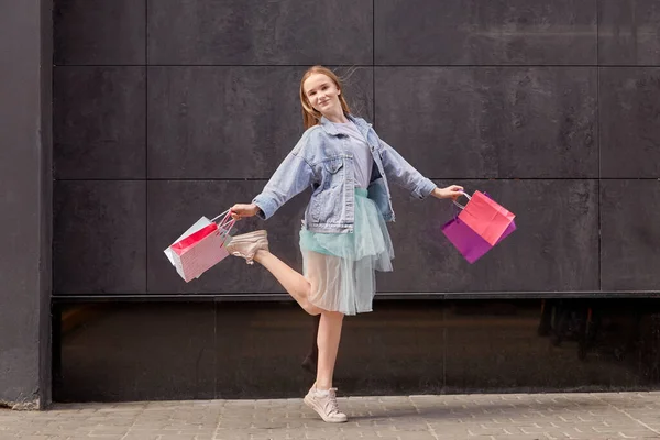 Молодая женщина держит в руках разноцветные сумки для покупок. Скручивание на месте. — стоковое фото