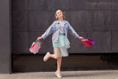 Parlak alışveriş torbalarıyla mutlu genç kız. Döndürme yerinde.