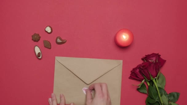 Kvinnors händer öppnas och läser ett kärleksbrev. Det står rosor på bordet.. — Stockvideo