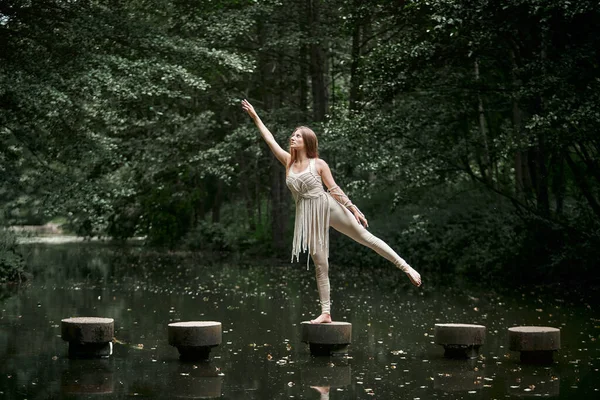 En ung kvinna i klänning står på en cirkel i vattnet och håller balansen. — Stockfoto