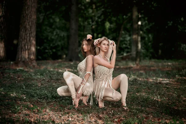 Två kvinnor sitter med ryggen mot varandra i beige klänningar. Kvinnor i kärlek. — Stockfoto