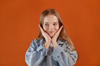 Şirin, kafası karışmış, uzun sarı saçlı, gülümseyen ve yüzünü çeviren bir kız..