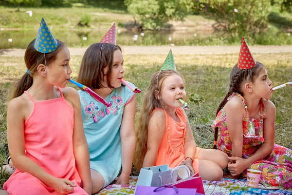 Négy lány ünnepi kalapban megünnepli a barátjának születésnapját a természetben nyáron.. — Stock Fotó
