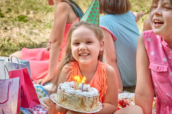 Vacker flicka som håller en tårta med brinnande ljus och tittar på kameran. — Stockfoto