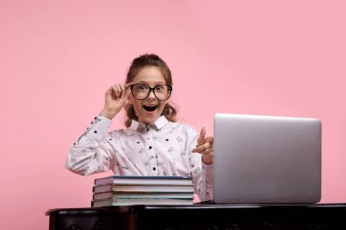 Güzel kız gözlük tutuyor. Masada dizüstü bilgisayarı olan bir kız..