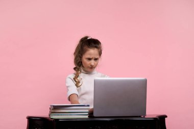 Masada oturan bir kız suratsız bir suratla bilgisayar ekranına bakar.