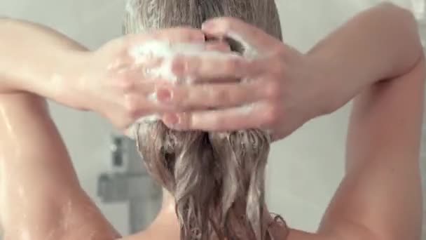 Nahaufnahme einer Frau, die ihre blonden Haare unter der Dusche wäscht. — Stockvideo